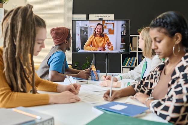 An individual participating in an online course, interacting with the instructor and fellow students remotely. The screen shows a virtual classroom with interactive elements and engaging content.